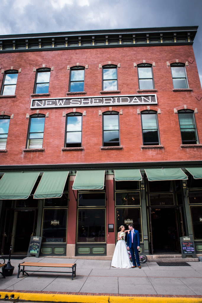 Bride and groom take portraits on main street at the new sheridan their Telluride wedding day.  Photographed by Telluride wedding photographer Real Life Photographs