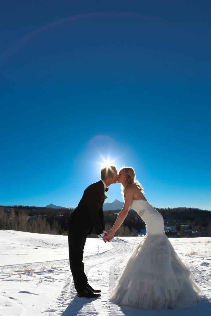 couple kisses with Wilson Peak in the back ground of their snowy portrait session.