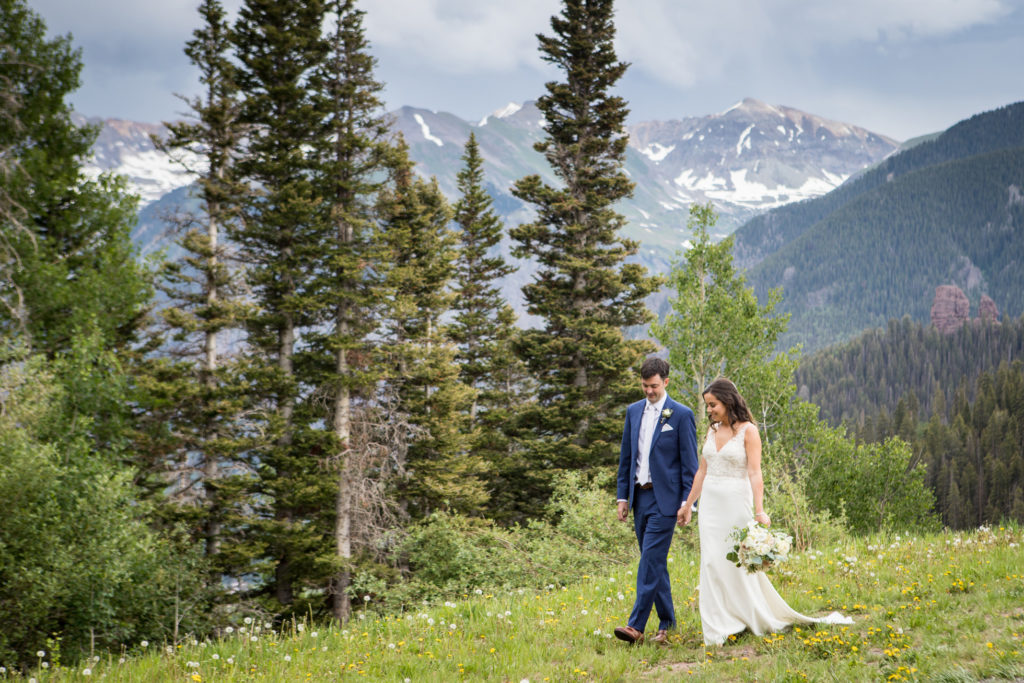 couple walks hand in hand at the top of Coonskin run on the Telluride ski area just moments after their first look