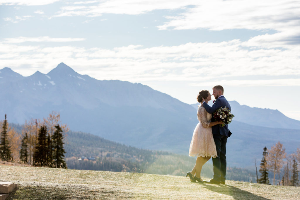 couple embraces in Telluride, Colorado with Mount Wilson in the back ground.