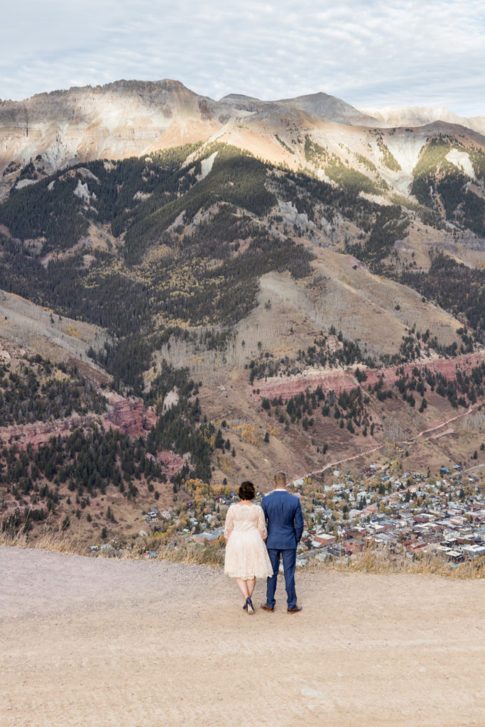 Elopement couple takes in the view at the top of Coonskin run with the town of Telluride in the background.