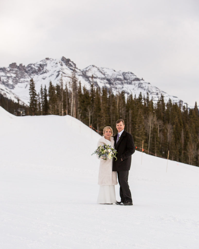 couple poses in the snow at San Sophia overlook with Palmyra peak in the background
