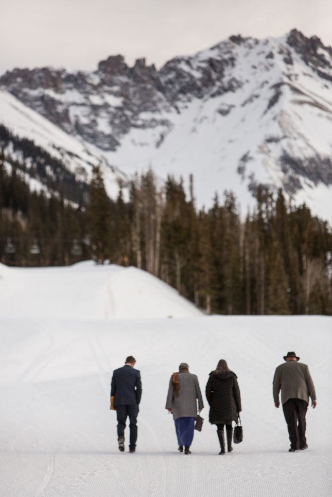 groom and 3 Telluride elopement guests walk to San Sophia Overlook with Palmyra peak in the background