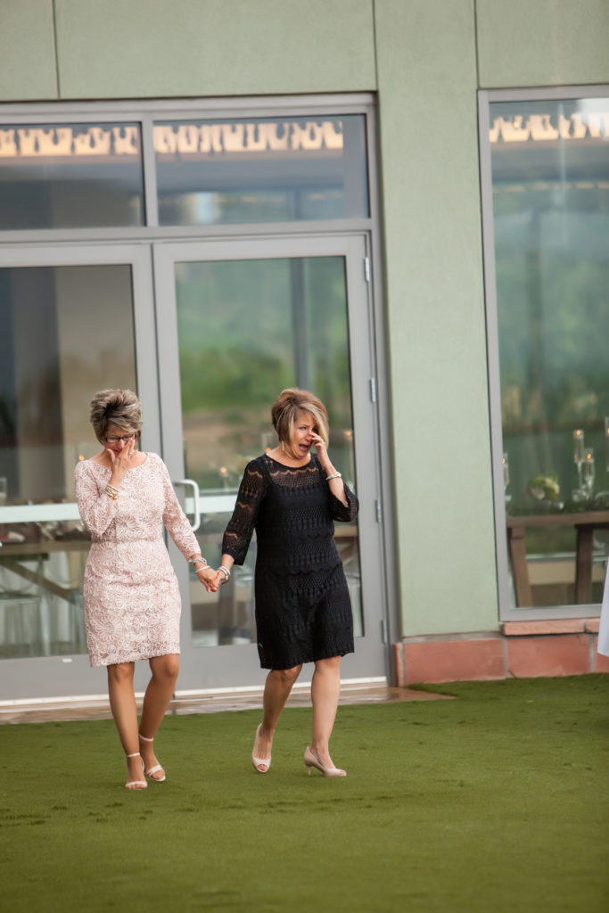 Mother of the bride and sister are emotional as they walk down the aisle