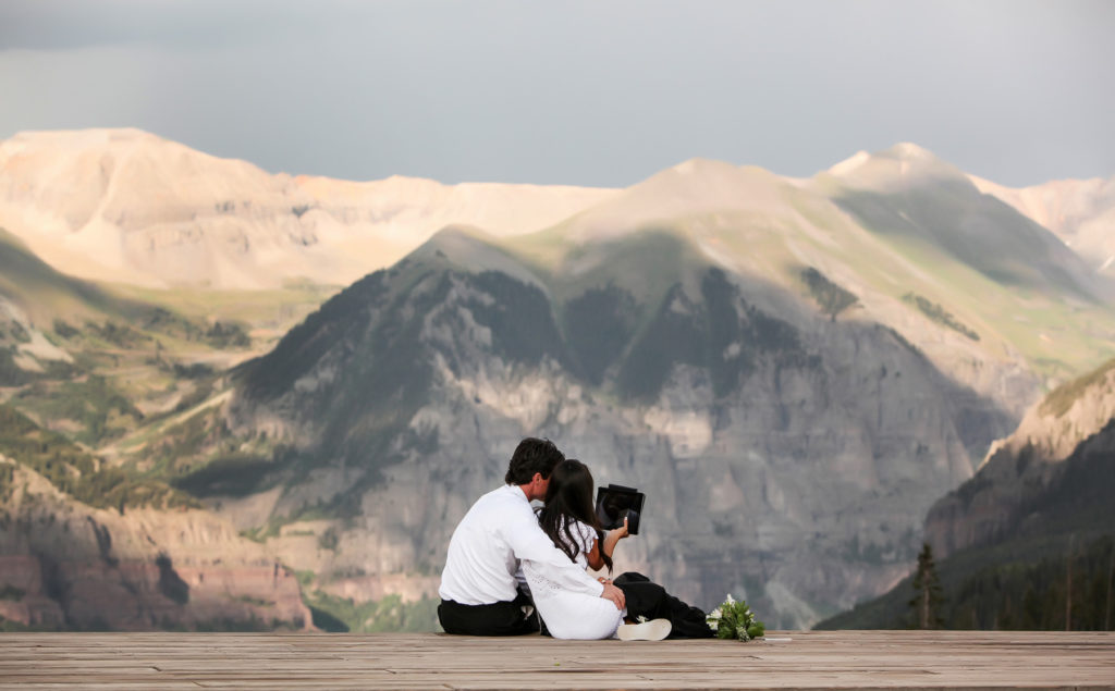 Eloping couple face times with their family from the deck at San Sophia Overlook