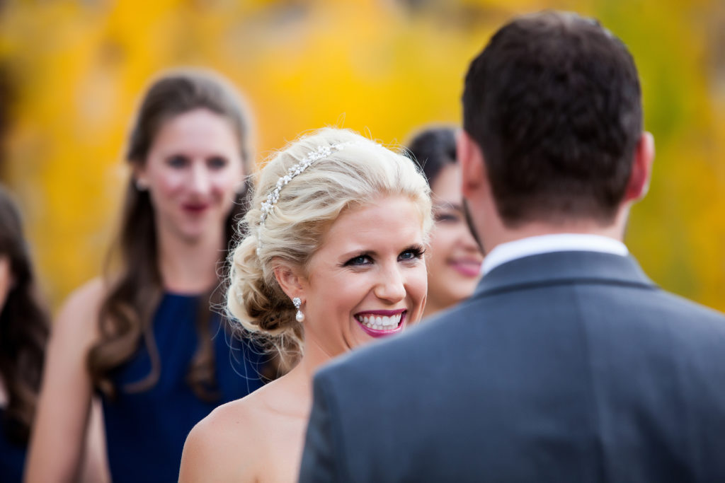 bride looks at groom during their Telluride wedding ceremony with the fall colors in the background