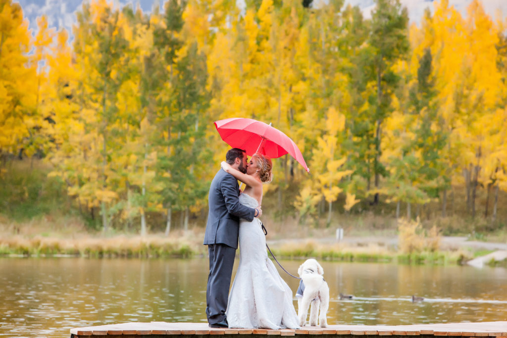 a Fall first look with a red umbrella and the gorgeous Telluride fall colors with a couple in Mountain Village and their dog