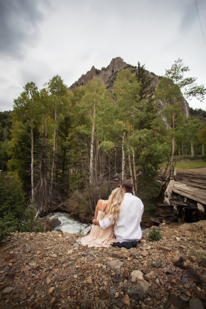 sitting next to the river in Ophir Colorado during their engagement session