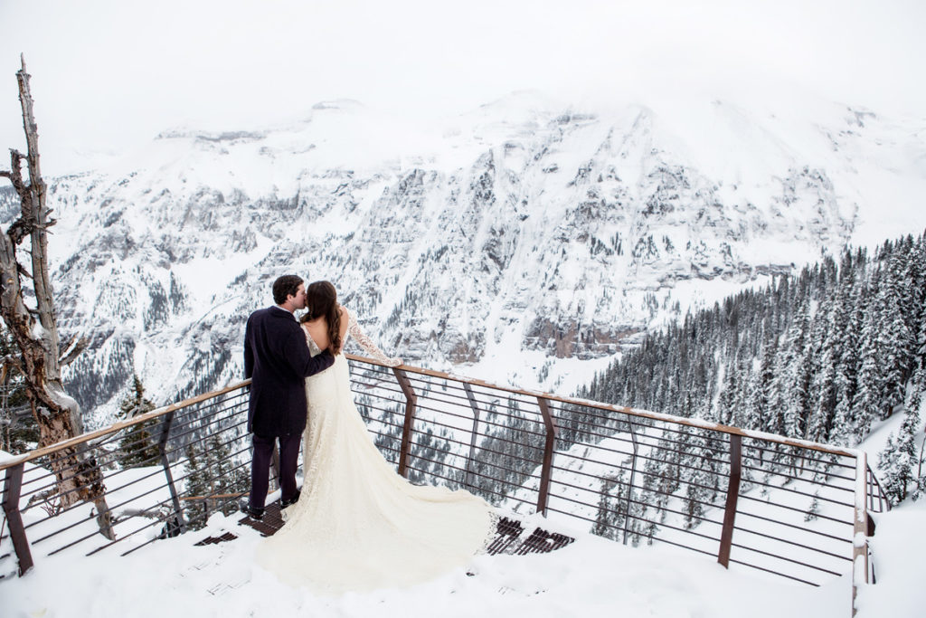 Telluride Tempter House bride and groom pose at 12,000 feet with the snowy mountains behind them