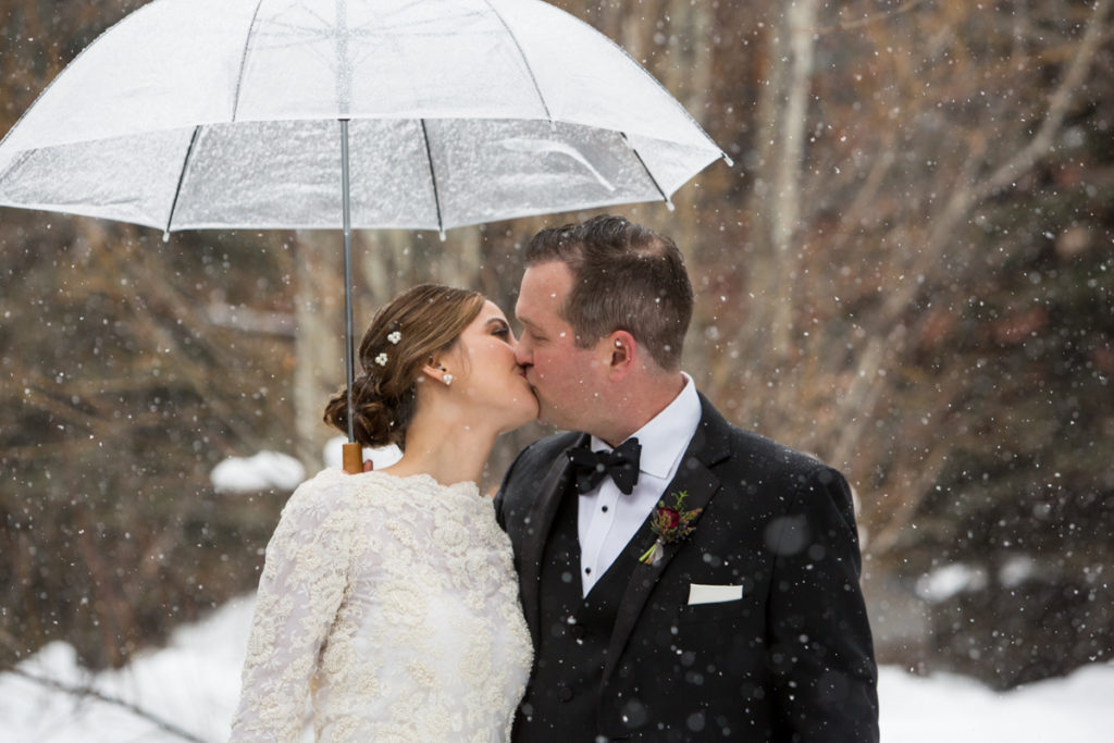 winter Telluride Peaks Wedding couple kisses under an umbrella